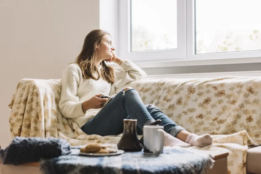 Heat recovery ventilation in an old house – is it a good solution, person sitting on a couch in a warm home during winter